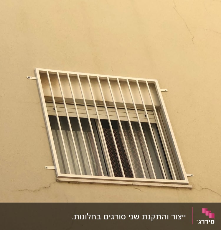 חלון עם סורגים לבנים על קיר חיצוני